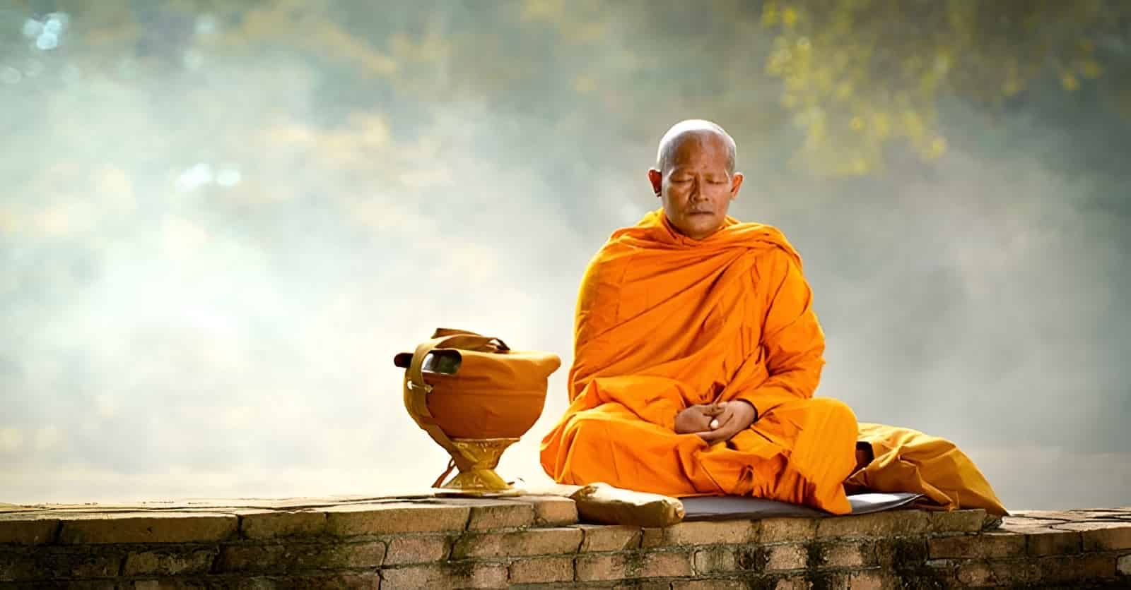 A Buddhist monk in traditional orange robes meditating in front of a temple A Buddhist monk in traditional orange robes meditating in front of a temple