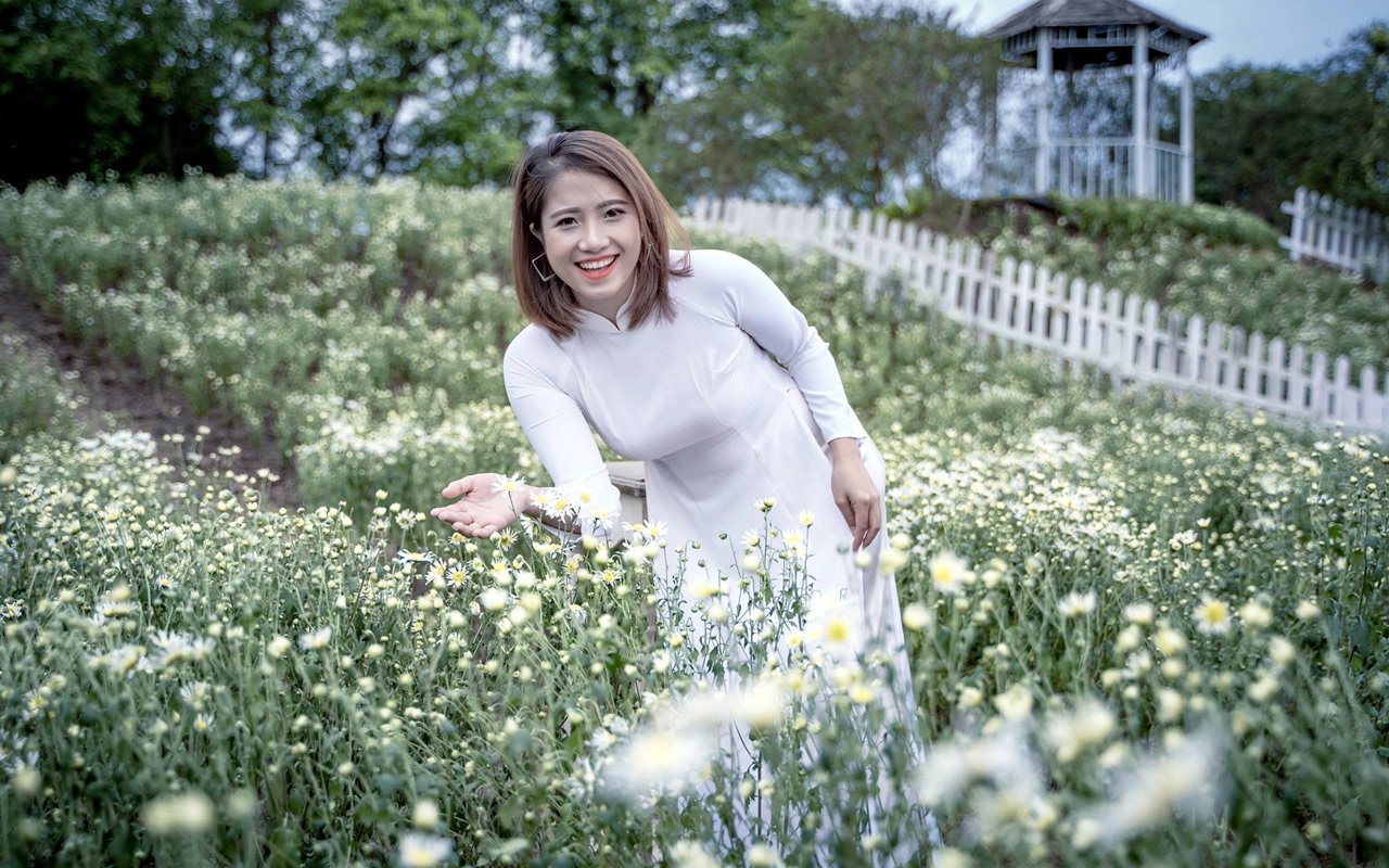 Vietnamese girl in Ao Dai in field of daisies