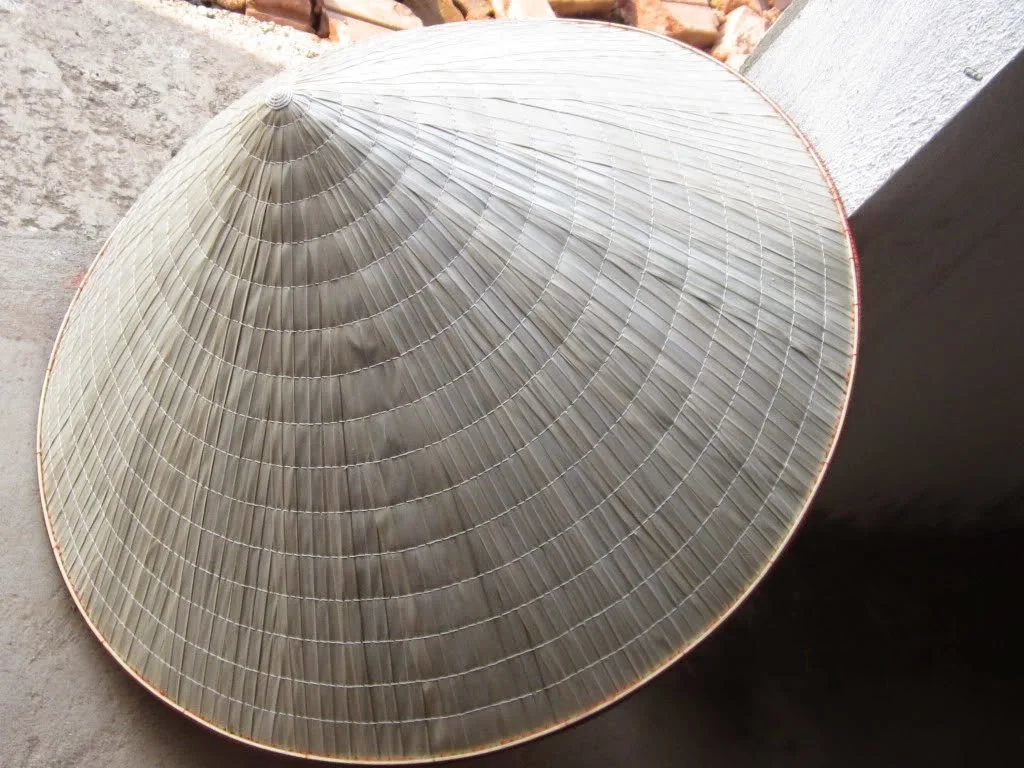 A photo of a Vietnamese conical hat. A photo of a Vietnamese conical hat. The hat is made of straw and has a conical shape. It is worn by people of all ages in Vietnam, and is a popular souvenir for tourists.