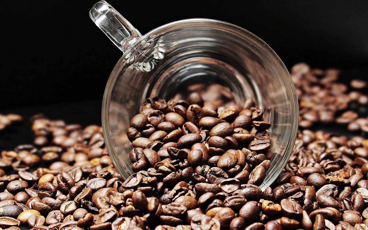 A close-up of roasted coffee beans in a glass cup A close-up of roasted coffee beans in a glass cup