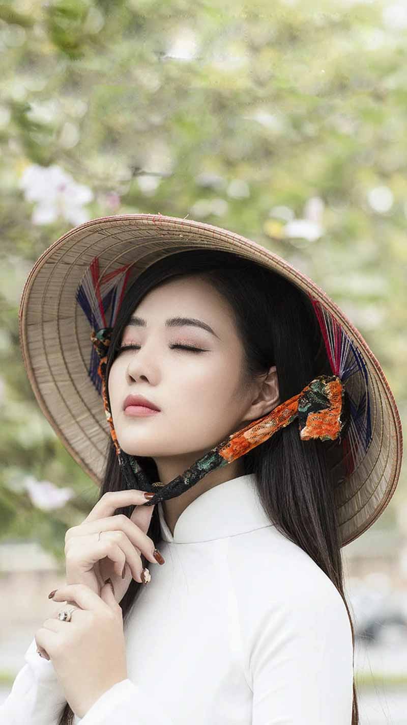 A beautiful Vietnamese girl is wearing a conical hat